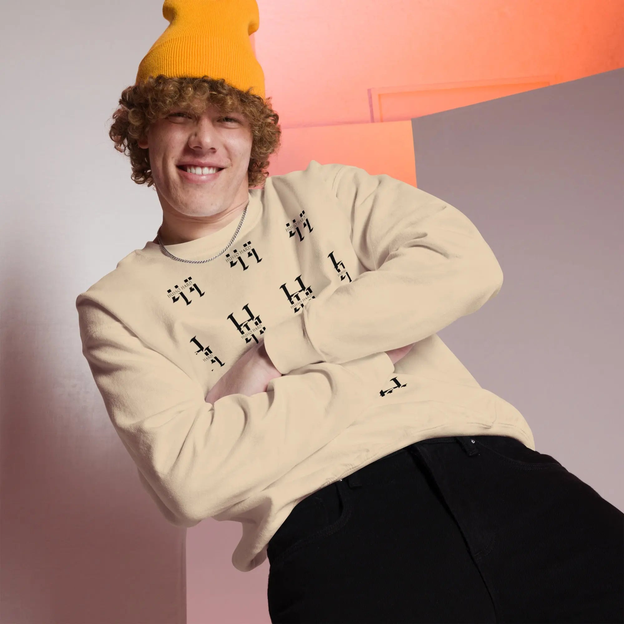 Man wearing cream Husso Hard all-over print sweatshirt with yellow beanie and black jeans