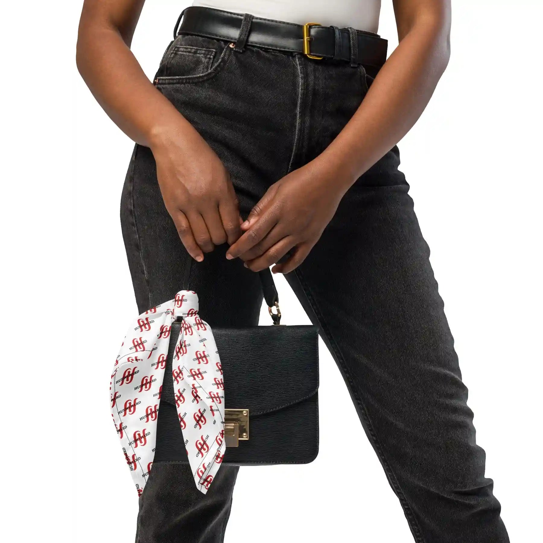 Black handbag with white Husso Hard printed scarf held by model in black jeans