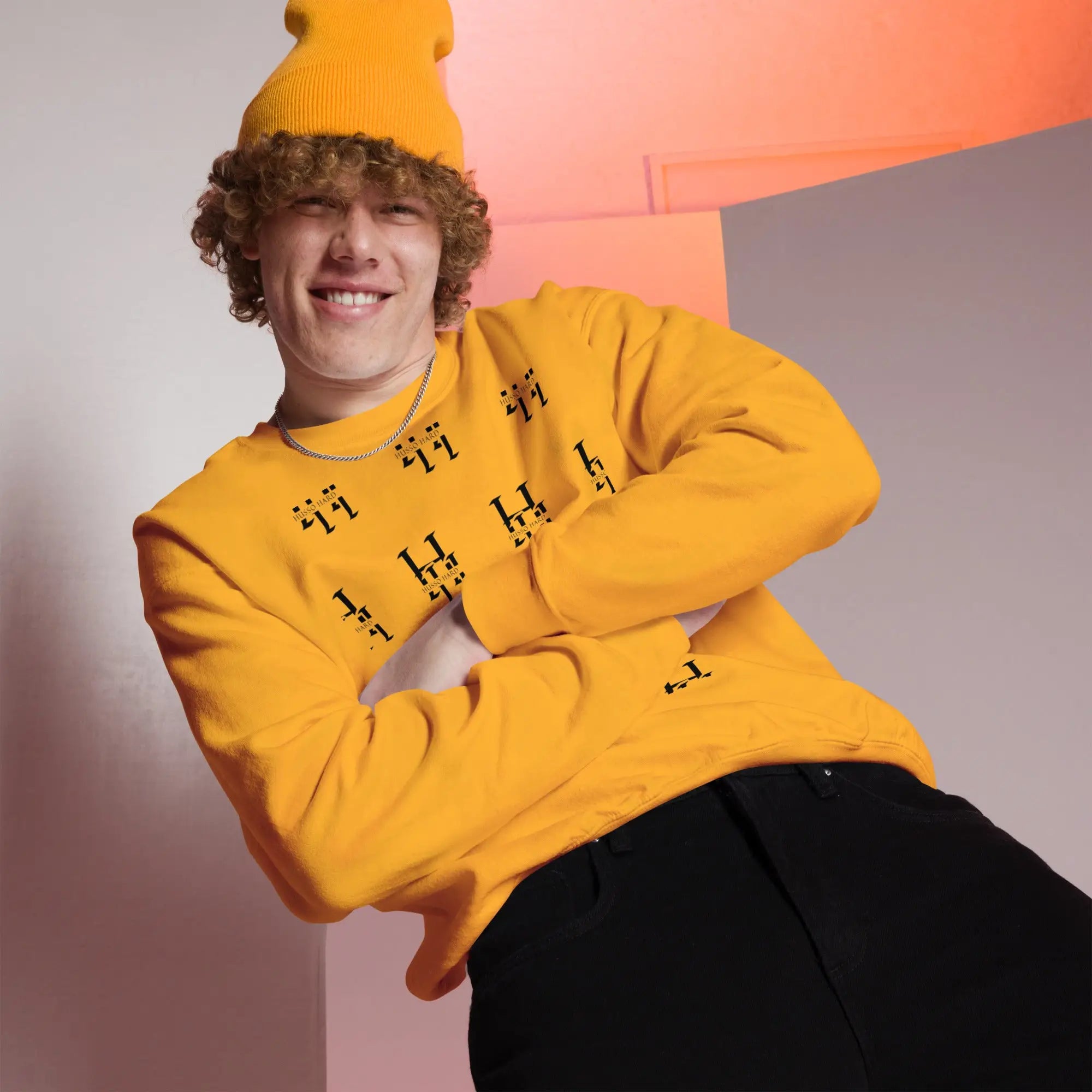 Man wearing yellow Husso Hard all-over print sweatshirt with yellow beanie and black jeans